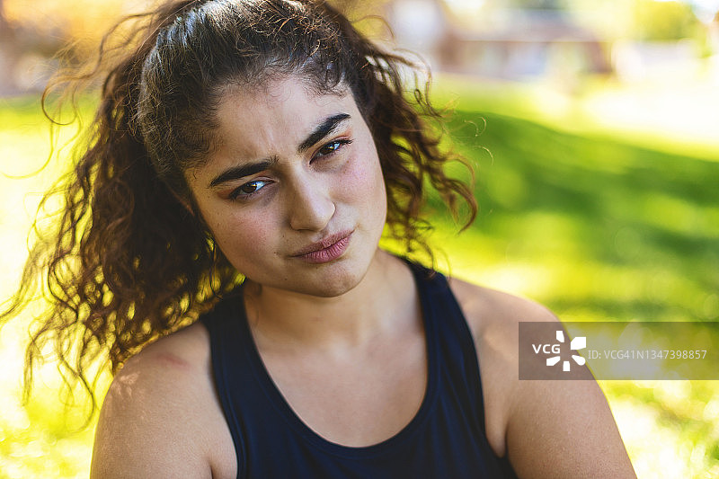 在自家前院放松的困惑拉丁裔少女，美国夏季生活方式照片系列图片素材