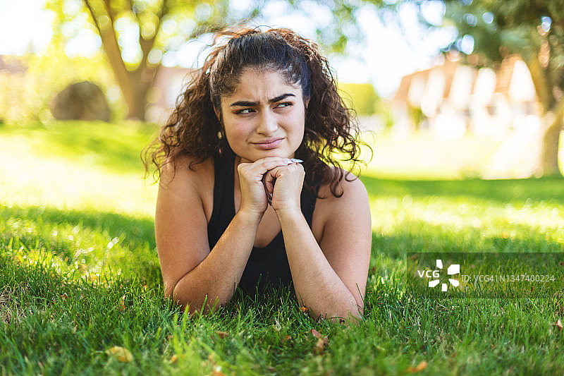 在夏季的前院放松的拉丁裔少女的烦恼表情，美国非裔拉丁生活方式摄影系列图片素材