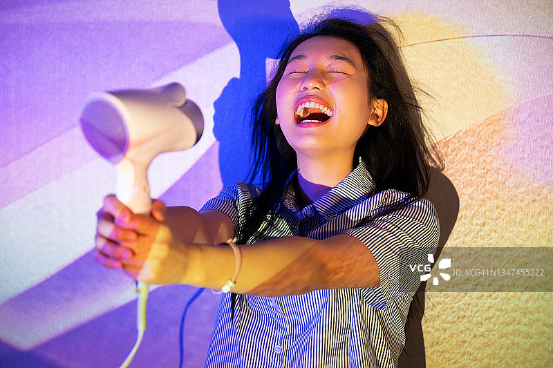 时尚女人光影下吹头发图片素材