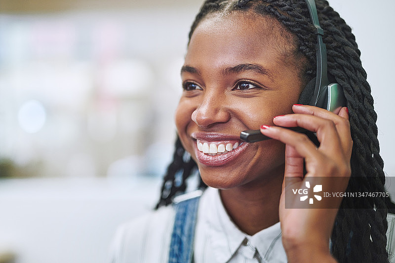 白天，有魅力的年轻女商人戴着耳机在办公室里图片素材