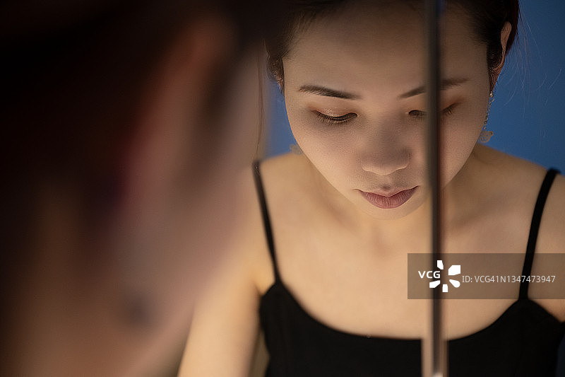 穿着吊带裙的美丽女人在镜子前化妆图片素材