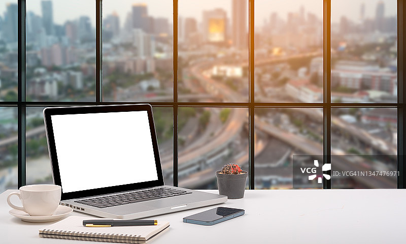 办公室内的笔记本电脑工作区，舒适的办公桌，城市景观视野图片素材