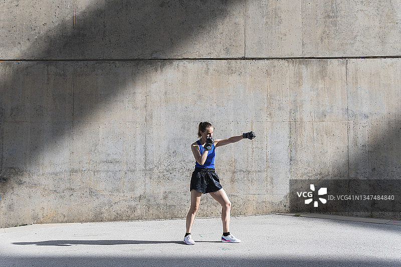女拳击手在墙前练习拳击图片素材