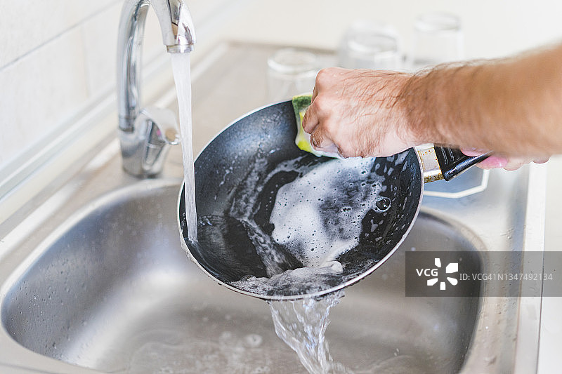 男子在厨房水槽清洁锅图片素材