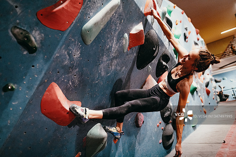 在抱石墙上攀爬的健壮女人 - 室内攀岩图片素材