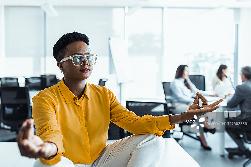 年轻的黑人女性在工作场所放松练习瑜伽，呼吸新鲜空气，平静的概念图片素材