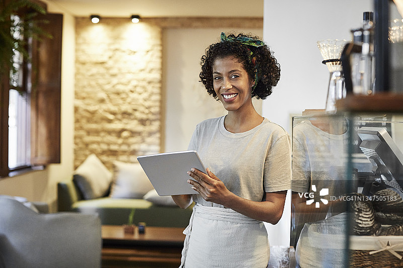 咖啡馆里使用平板电脑的微笑店主图片素材