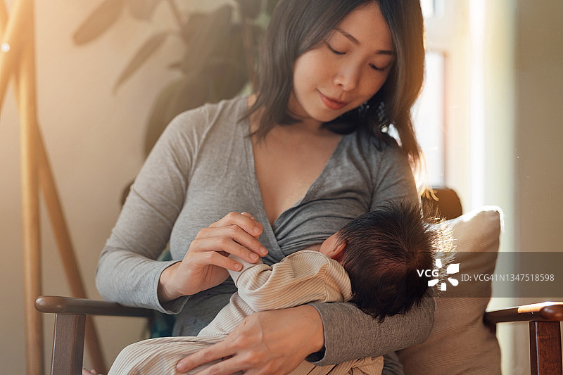 阳光明媚的早晨，母亲在家中给宝宝喂奶图片素材