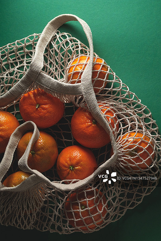 环保袋中未成熟橘子，绿色背景图片素材