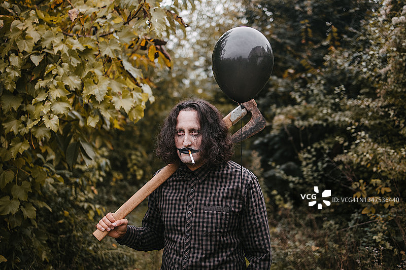 手持斧头和黑色气球的恐怖男人图片素材