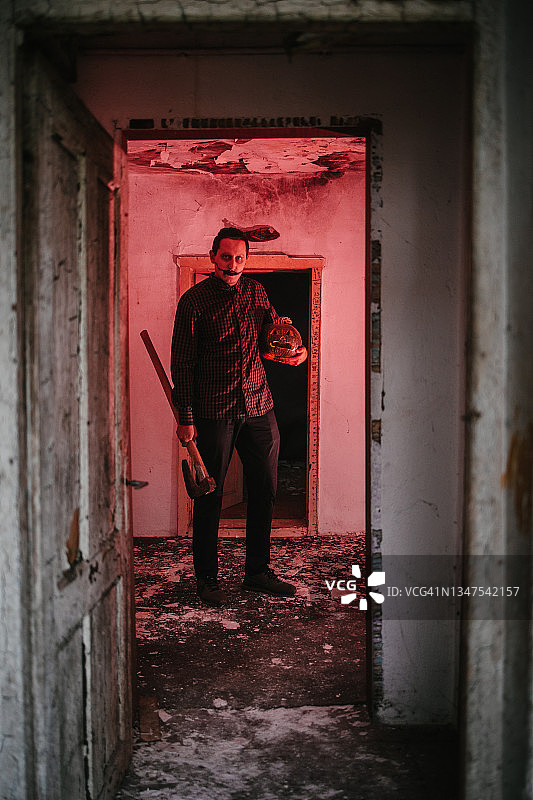 站在红色灯光房间里拿着斧头的男人图片素材