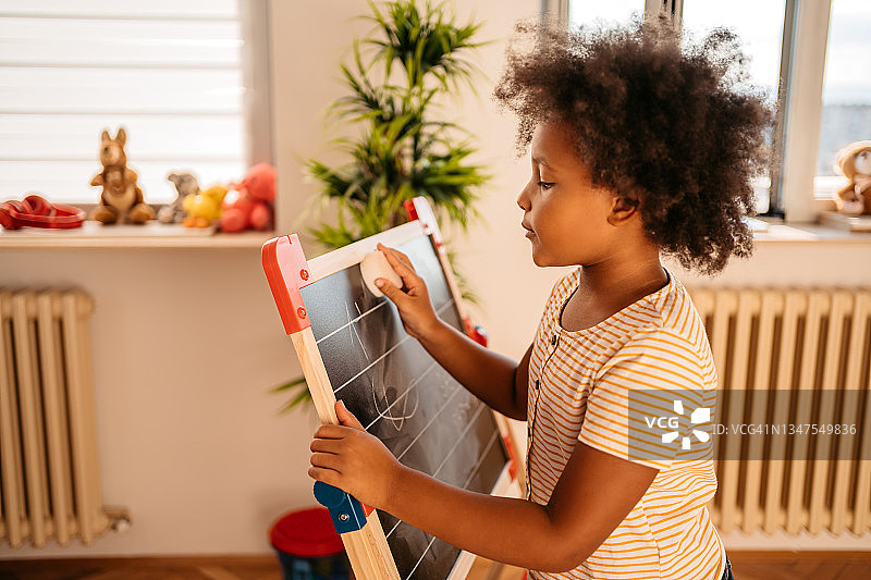 小女孩在家在黑板上绘画图片素材