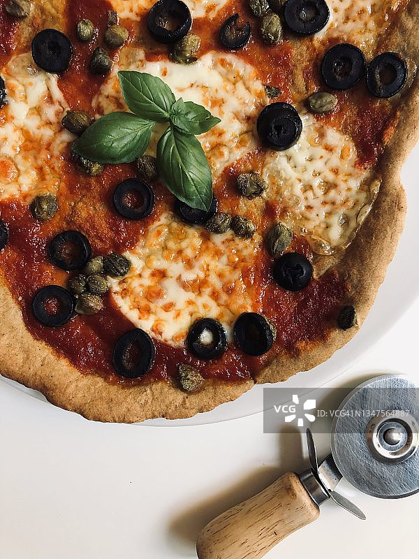 一份含有橄榄、刺山柑、马苏里拉奶酪、番茄和罗勒的披萨的俯视图图片素材