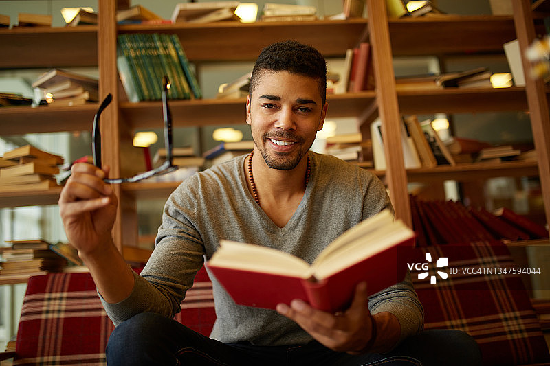 微笑的非裔美国学生在图书馆享受阅读图片素材