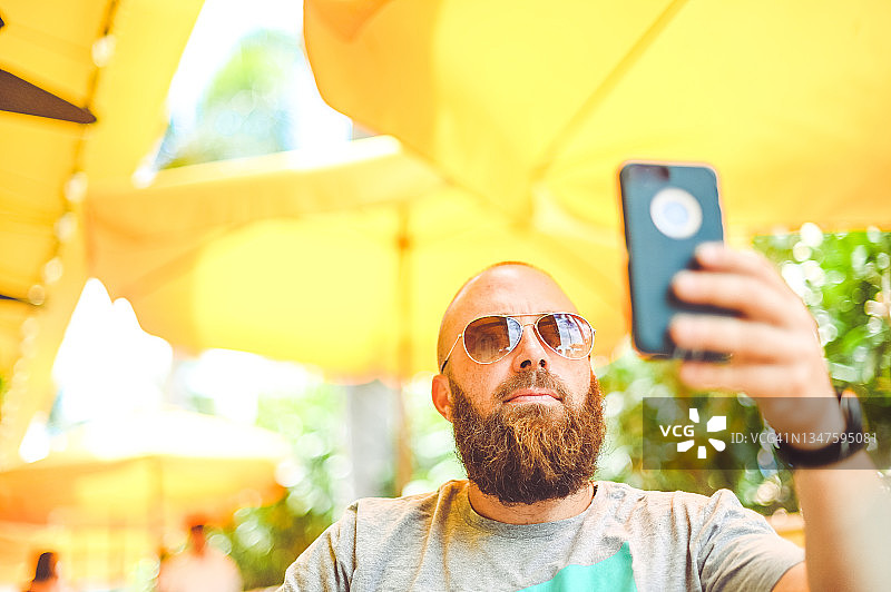 男人在阳光明媚的黄色户外咖啡馆或餐厅使用手机图片素材