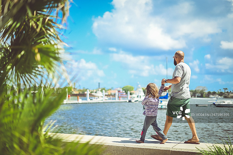 父女在阳光明媚的热带地区海滨散步图片素材