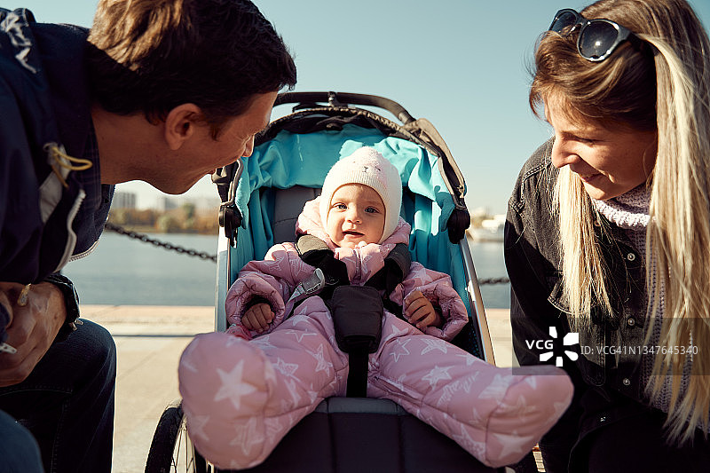 情侣推着婴儿车坐在堤岸的长椅上图片素材