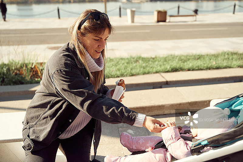 年轻母亲在堤坝边婴儿车里哄宝宝图片素材