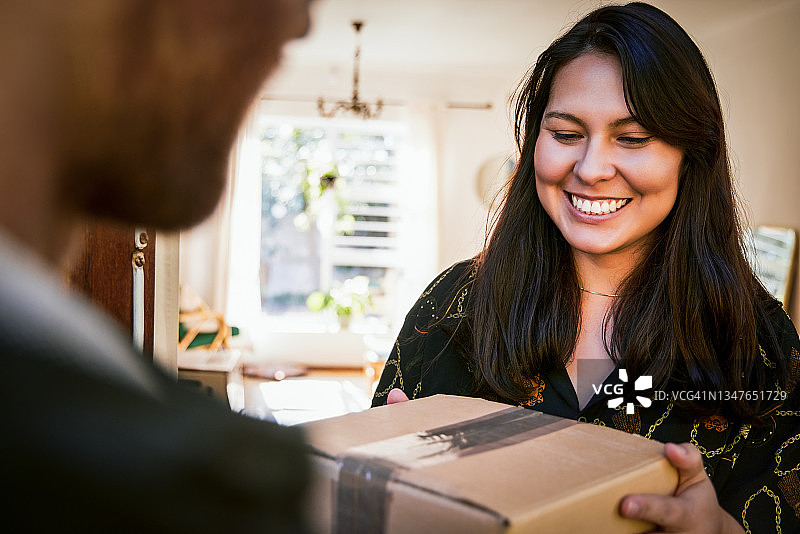 快递员送货上门，年轻漂亮的女子在家收包裹特写图片素材