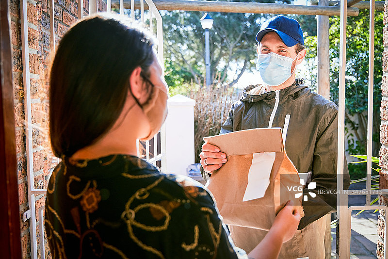 年轻快递员为女顾客送货上门图片素材