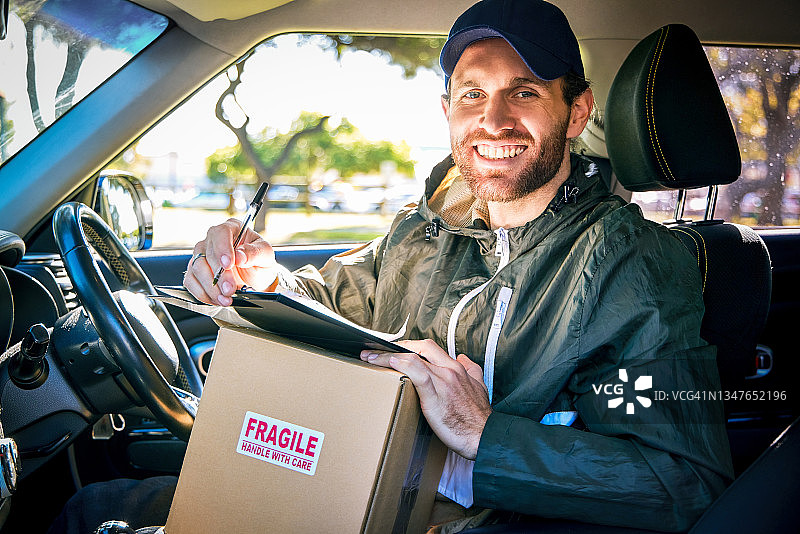 英俊的年轻男快递员驾驶货车送货的局部肖像图片素材