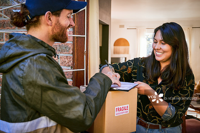 快递员送货上门，年轻漂亮的女子在家收包裹特写图片素材