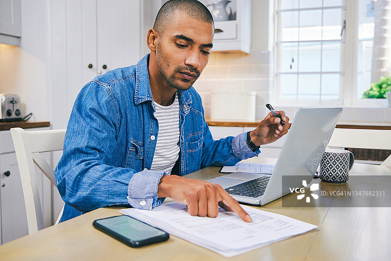 年轻男子在家使用笔记本电脑处理文件的镜头图片素材