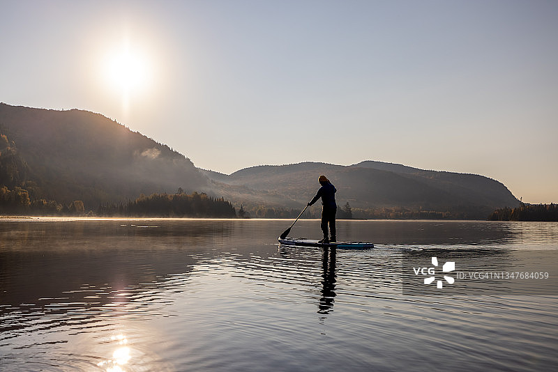 男人在魁北克省翠湖山省立公园的湖上划桨板（秋季）图片素材