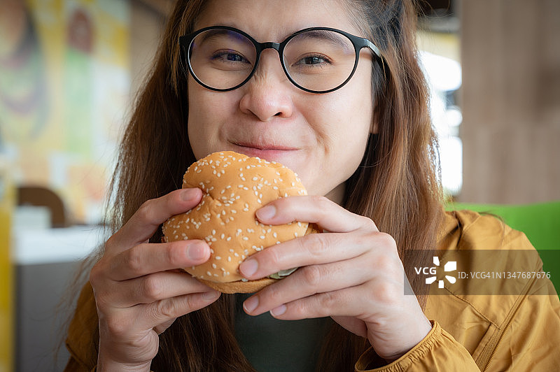 年轻亚洲女性手拿汉堡准备食用图片素材