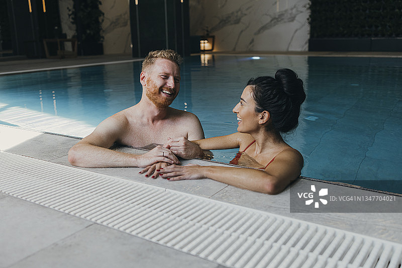 快乐情侣在酒店泳池玩耍图片素材