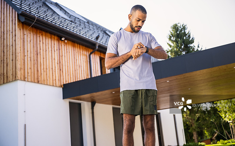 跑步前查看手表的健壮男跑步者图片素材