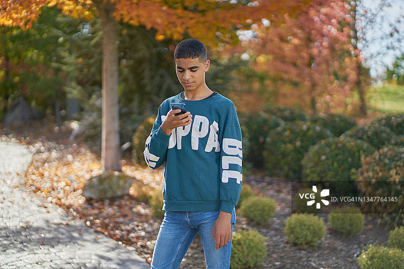 在公园户外使用手机的摩洛哥男人，科技概念图片素材