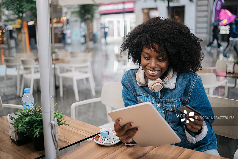 在户外使用笔记本电脑和信用卡的年轻西班牙裔黑人女性图片素材