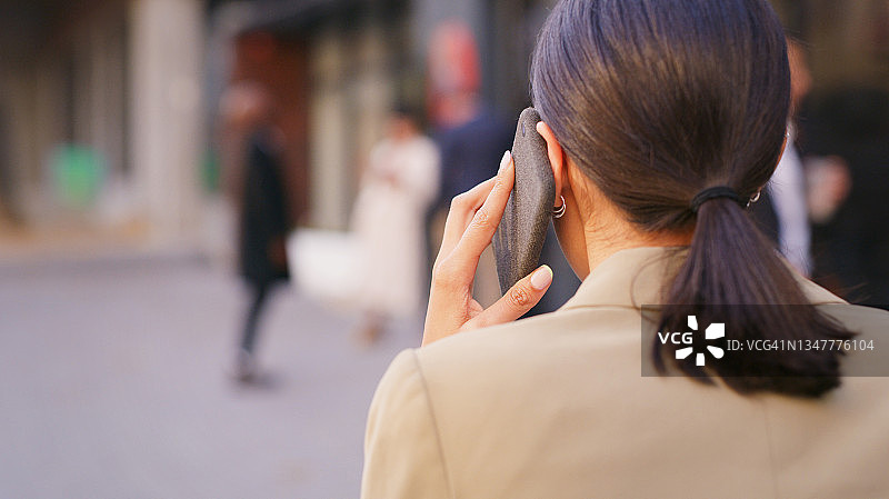 女商人走在城市里使用智能手机的照片图片素材