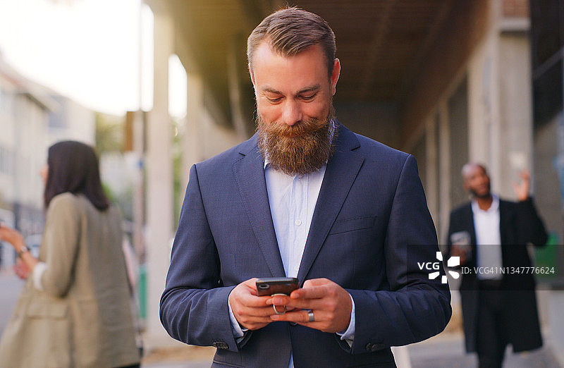 年轻商人走在城市中使用智能手机图片素材