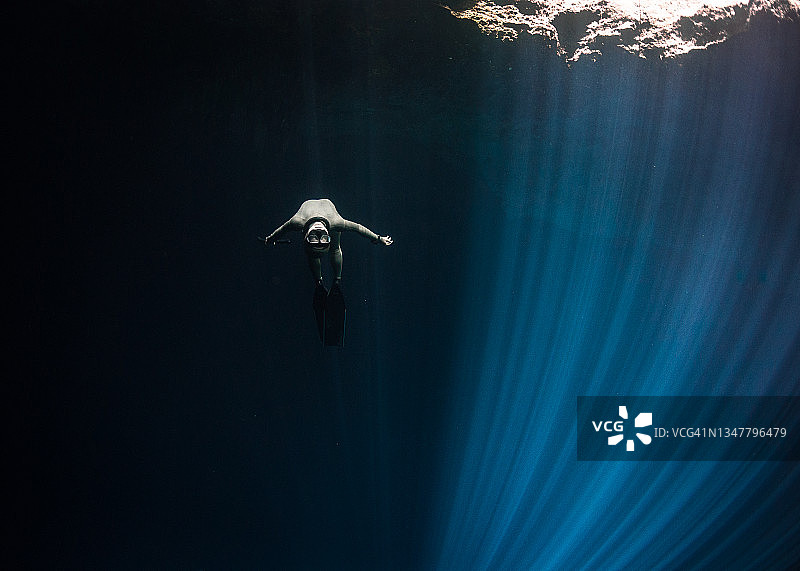 在灰岩坑水面游泳的自由潜水员图片素材