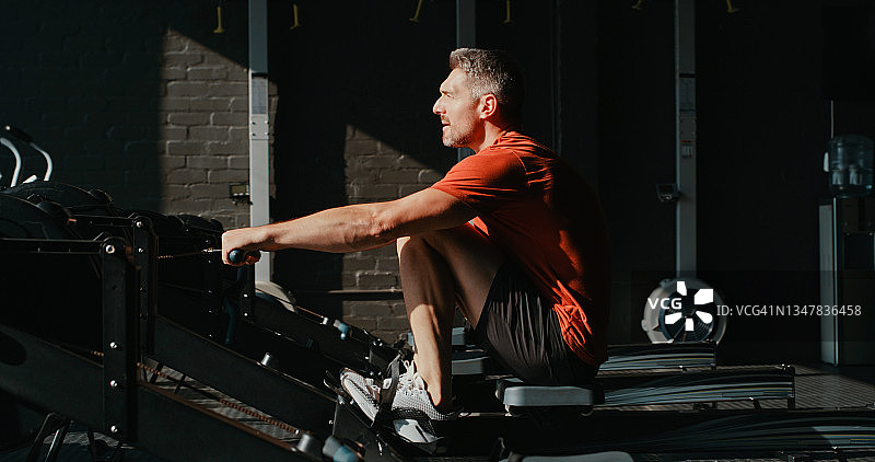 成熟男士在健身房使用划船器锻炼图片素材