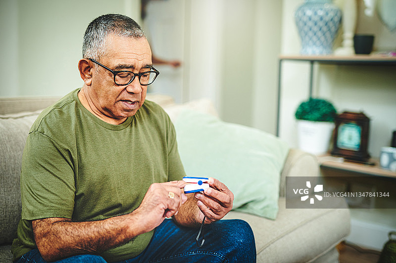 年长的男人在家使用脉搏血氧仪的照片图片素材