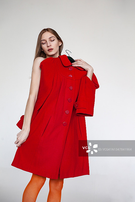 在工作室试穿红色外套的时尚女人图片素材