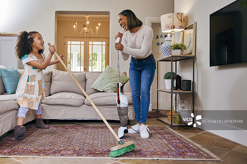 母亲和女儿在清洁客厅时玩得很开心图片素材