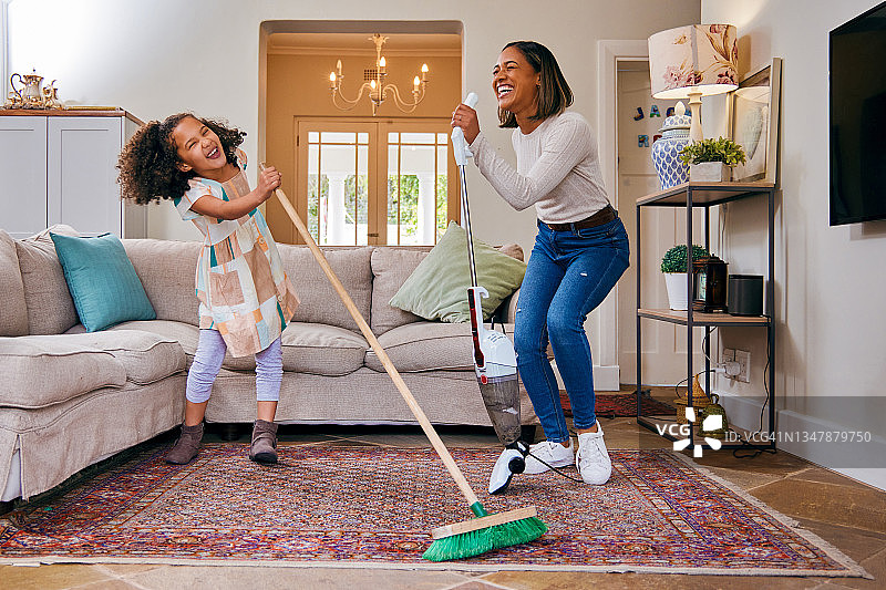 母亲和女儿在清洁客厅时玩得很开心图片素材