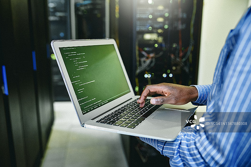 在服务器机房工作时，男子使用笔记本电脑的特写镜头图片素材