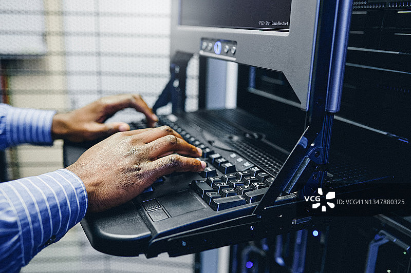 一位身份不明的男子在服务器机房里操作电脑的特写镜头图片素材