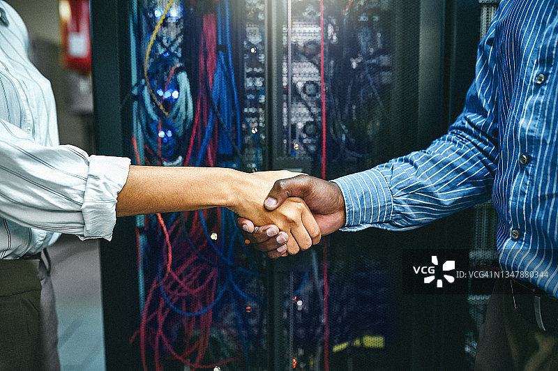 服务器机房内两位技术人员握手的特写镜头图片素材