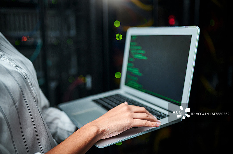 在服务器机房使用笔记本电脑的匿名女子特写图片素材