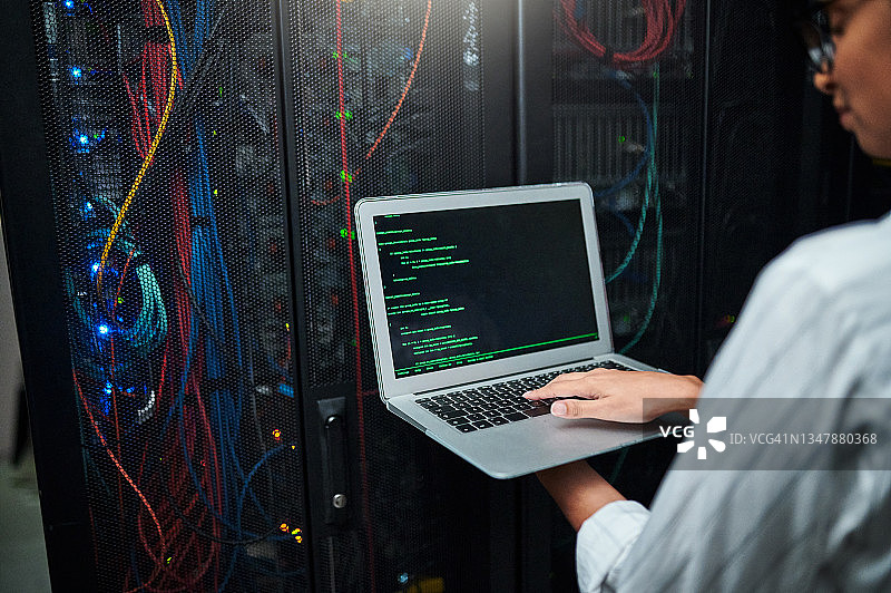 在服务器机房使用笔记本电脑的匿名女子特写图片素材