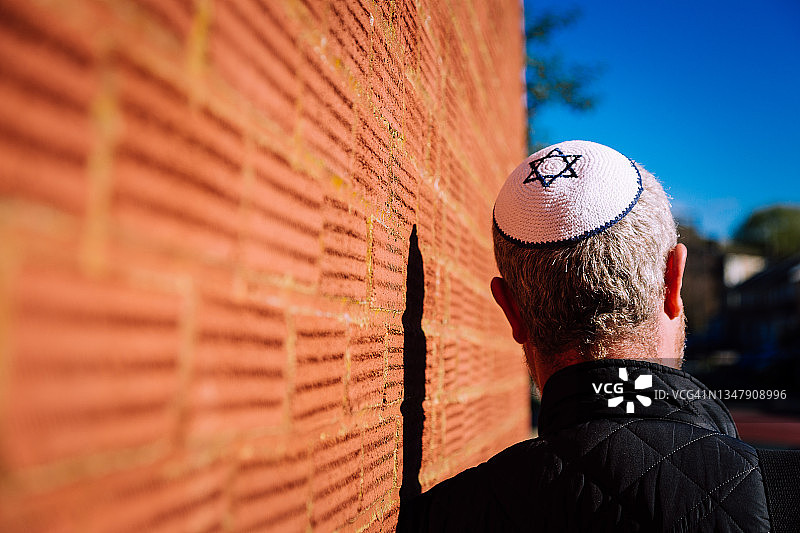 一个戴着小圆帽的犹太男人走在城市街道上图片素材