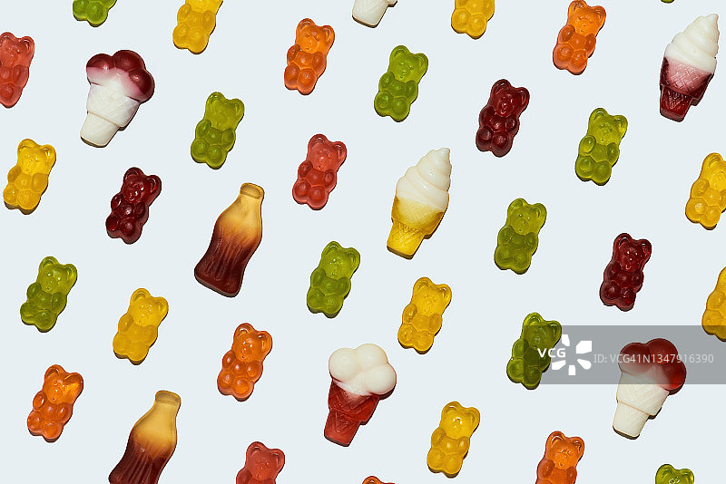 各种美味的熊形和冰淇淋形软糖特写，在白色背景上呈对角线排列图片素材