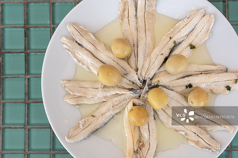 白色盘子，配以橄榄油和醋腌制的凤尾鱼及橄榄图片素材