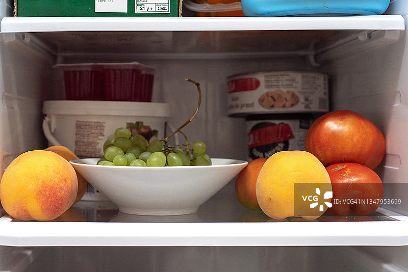 冰箱里的架子，前景是新鲜水果，背景是一些罐头食品图片素材